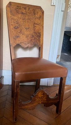 a wooden chair with a brown leather seat in a room