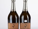 deux bouteilles de champagne posées l'une à côté de l'autre sur une surface blanche
