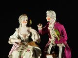 two figurines of a man and a woman sitting on a bench