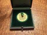 a green box with a gold coin in it on a wooden table