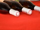 four bottles of wine are lined up on a red table cloth