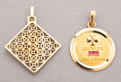 two gold pendants of different shapes and sizes on a gray surface