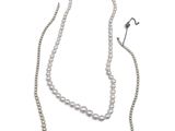 two strands of white pearls and a silver chain on a white background