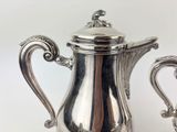 a silver coffee pot with a handle on a table