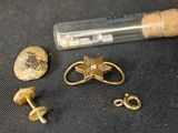 une petite bouteille accompagnée de quelques objets en or posés sur une table