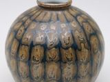 un vase bleu et brun posé sur une surface blanche