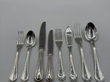 five forks, a knife, a spoon, and a spoon rest on a table
