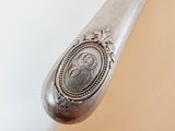 an old silver spoon with a silver handle on a white surface