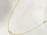 a close up of a gold necklace with diamonds on a white background