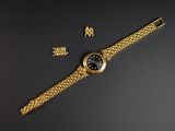 gros plan d'une montre en or sur une surface noire