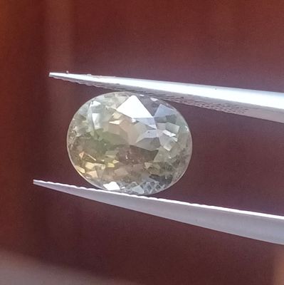 un diamant vert et blanc maintenu par une pince
