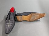 pair of men ' s shoes with red soles on a grey surface