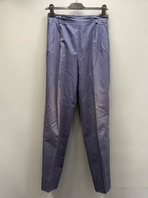 un pantalon violet suspendu à un cintre devant un mur blanc