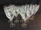 six verres à vin transparents sont alignés sur une surface noire