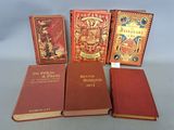 four books are lined up on a table, one is red and the other is gold