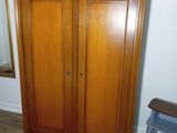 a wooden armoire in the corner of a room