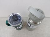 a silver and green coffee cup next to a green and white coffee cup