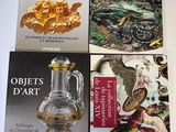 trois livres posés sur une table, avec un vase doré et d'autres objets