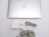an apple laptop computer sitting on top of a white table next to a charger