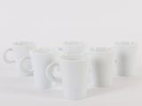 six white coffee mugs lined up in a row on a white surface