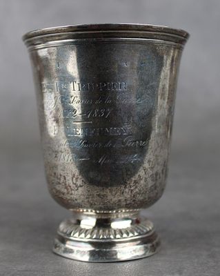 une vieille coupe en argent posée sur une table près d'un mur gris