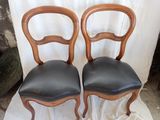 pair of black leather dining chairs on a white cloth