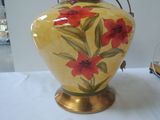 yellow vase with red flowers on it sitting on a white table