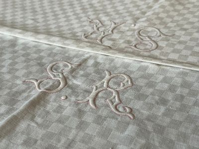 two monograms on a bed sheet with a checkered pattern