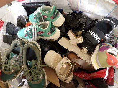 de nombreuses paires de chaussures dans un panier posé sur un lit