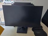 a computer monitor sitting on a desk in front of a window