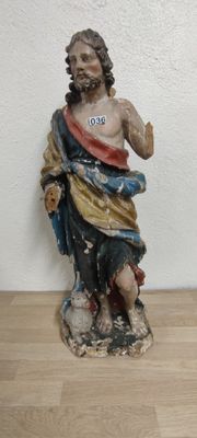 une statue de Jésus assis sur un plancher en bois, près d'un mur