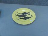 une assiette jaune sur laquelle est posé un poisson, posée sur une table