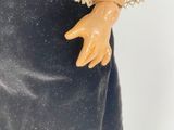 a close up of a doll wearing a dress and hat