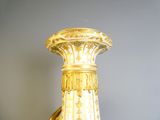 a gold and white vase sitting on a shelf next to a wall