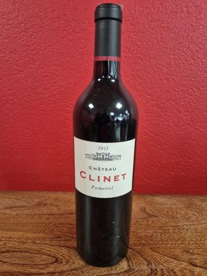 La bouteille de vin est posée sur la table, devant un mur rouge.
