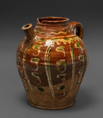 a brown vase with green and yellow designs on it