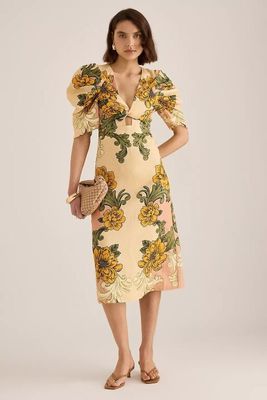 une femme vêtue d'une robe jaune à fleurs prend la pose pour une photo