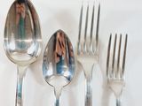 four silver spoons and two silver spoons on a white table