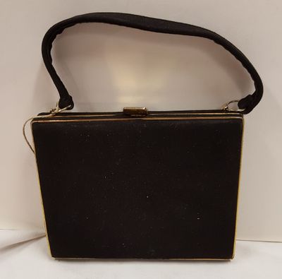 black purse with gold trim and handle on a white surface