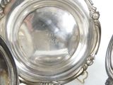 a silver plate sitting on top of a table next to other silver dishes