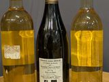 three bottles of wine are lined up on a wooden table