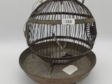 a bird cage with a bird inside of it on a plate