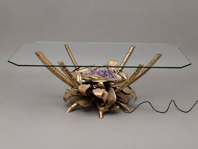 une table en verre sur laquelle est posée une fleur dorée