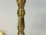 a close up of a gold colored lamp on a white table