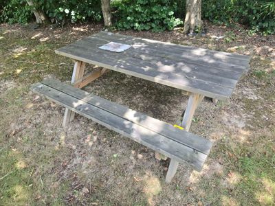 a picnic table with a sign on it in the grass