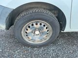 une camionnette blanche avec un pneu crevé sur une route en gravier