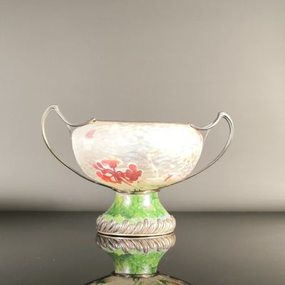 a green and white vase with a red flower on it