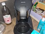 une cafetière noire posée sur un plan de travail, à côté d'une bouteille d'eau
