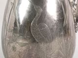 a silver pitcher with a bird design on it
