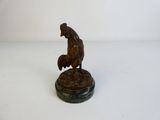 une statue antique en bronze représentant un coq, posée sur un socle en marbre